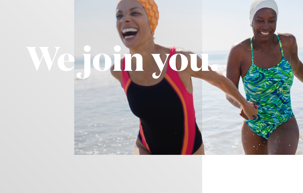 Aetna brand tagline - We join you - two woman laughing and running on in the shallows of the ocean seashore